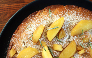 rosemary apple cake sitting on a dark dish on a wooden surface
